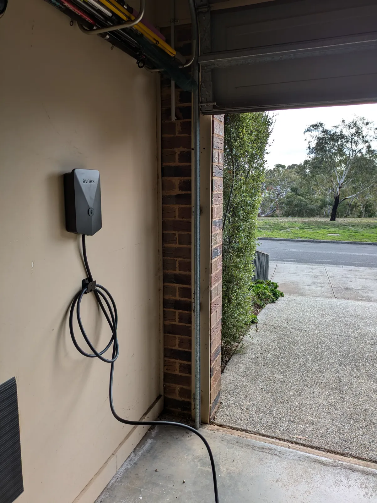 A home charger mounted inside a garage, cable holstered