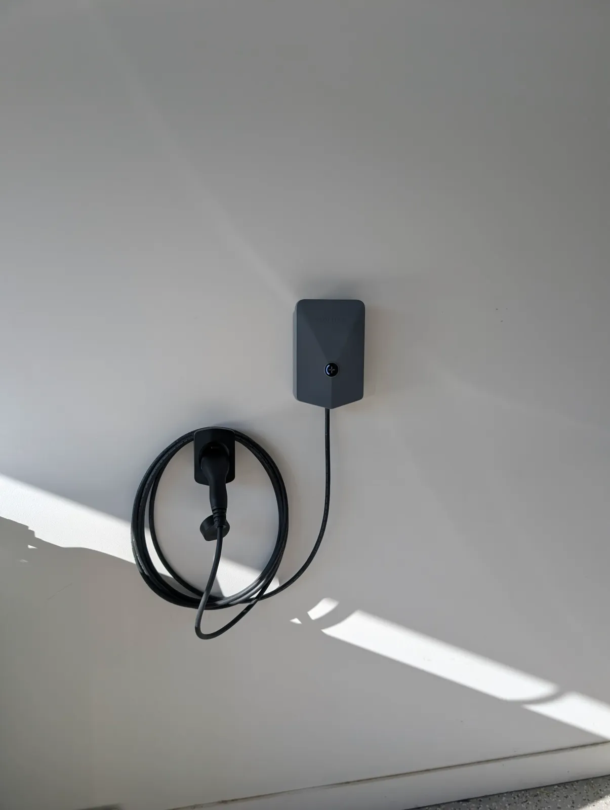 A home EV charger on a rendered wall, cable coiled