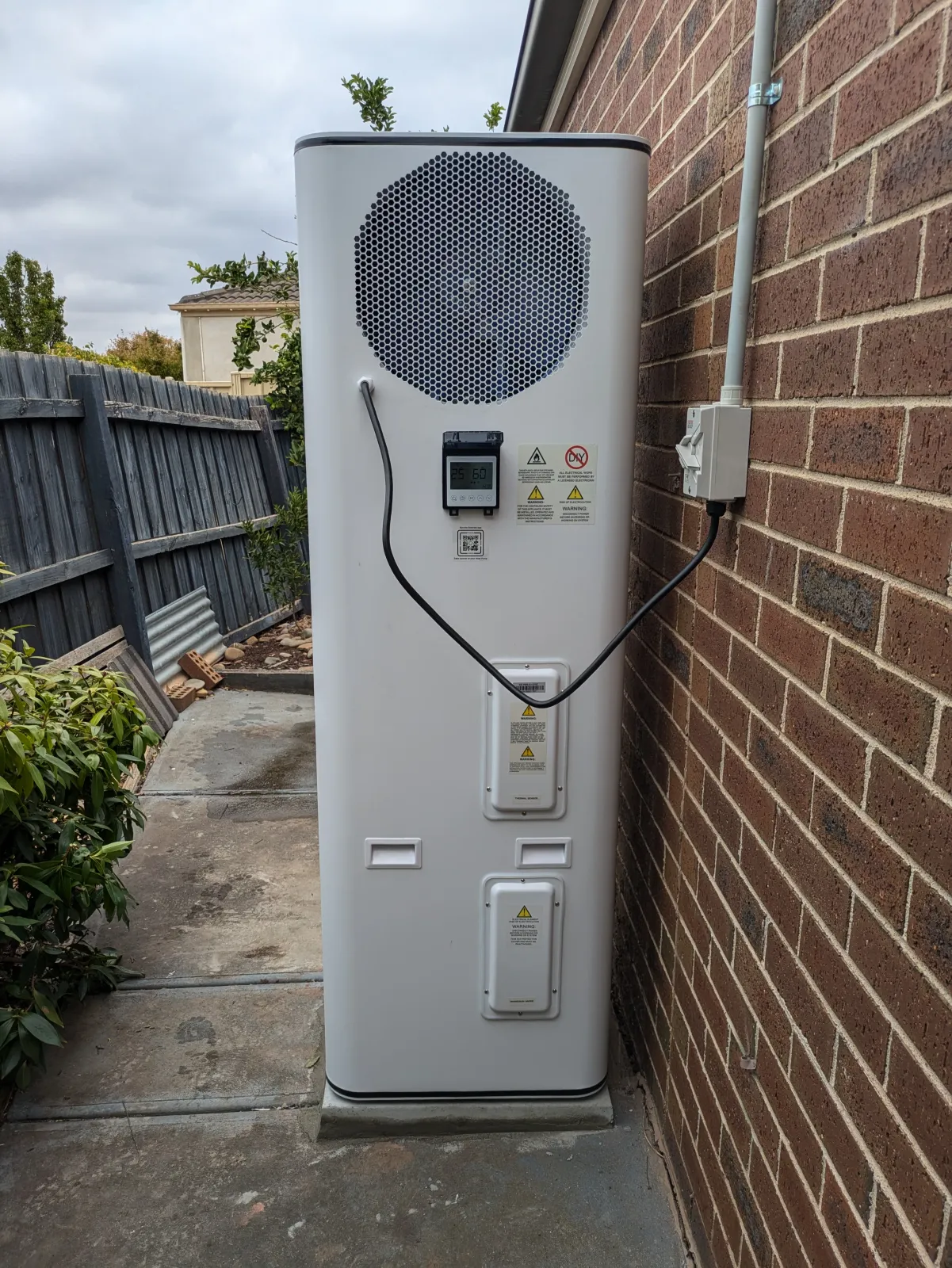 A heat pump sited clear of windows on a brick wall