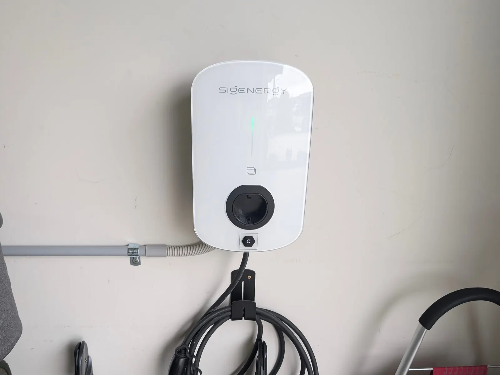 A Sigenergy EV charger on a garage wall with the cable holstered