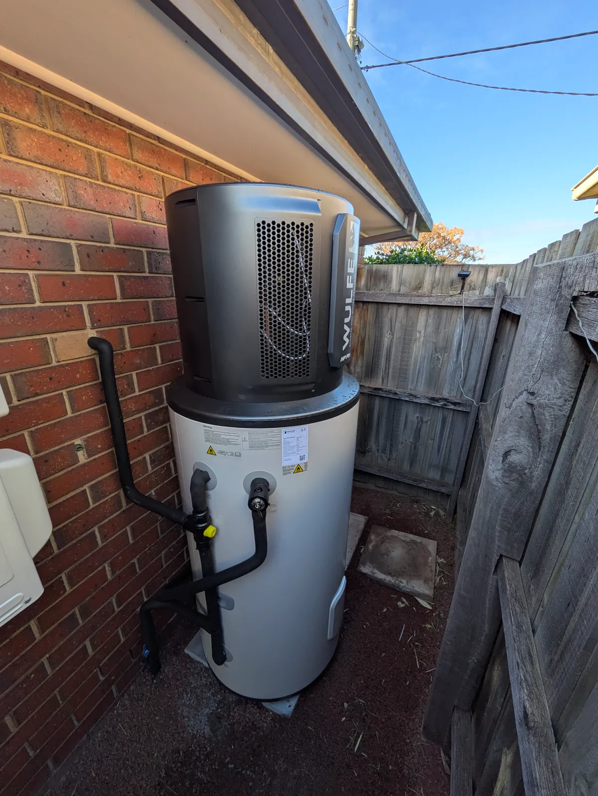 A Wulfe heat pump hot water unit installed in a narrow side passage