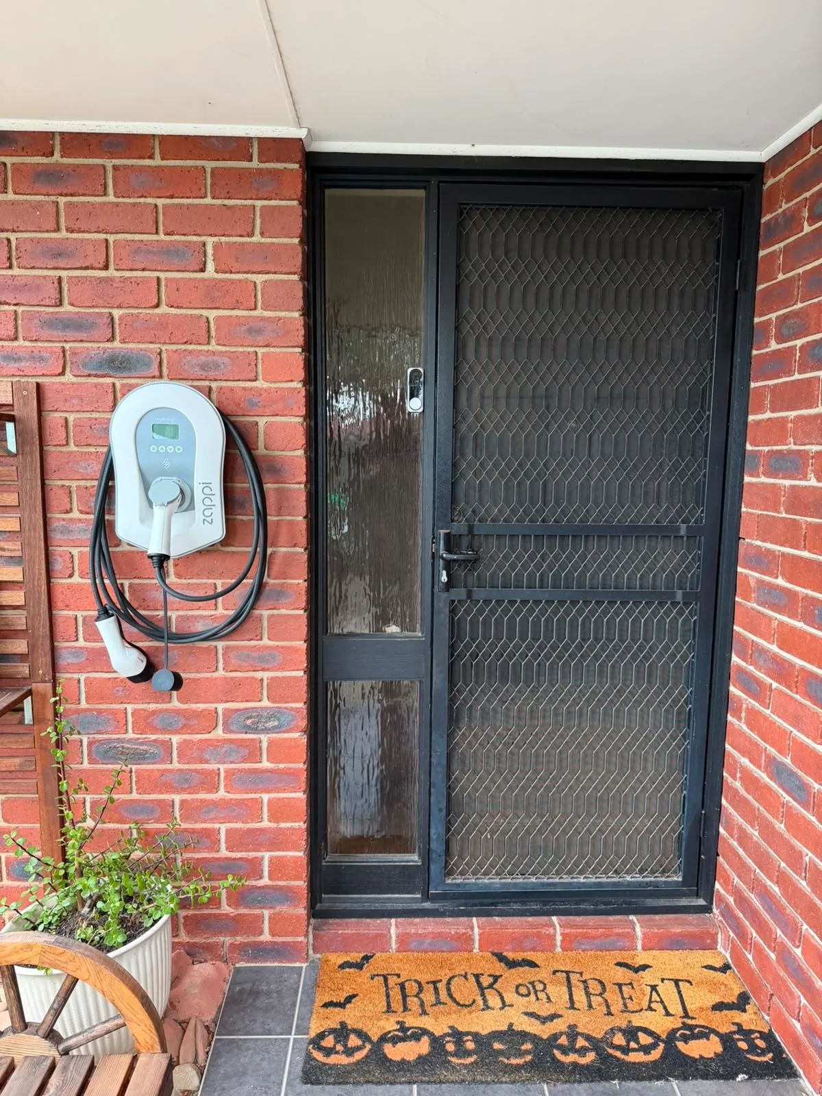 Sited beside the front door, conduit kept tight to the brick